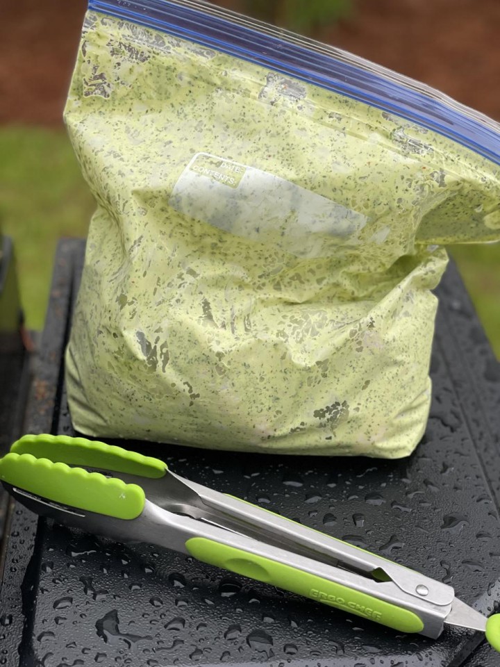 In this photograph by Elizabeth Karmel, a re-closeable plastic bag holds a light green marinade of Chimichurri sauce and mayo and chicken wings ready for the grill. 
