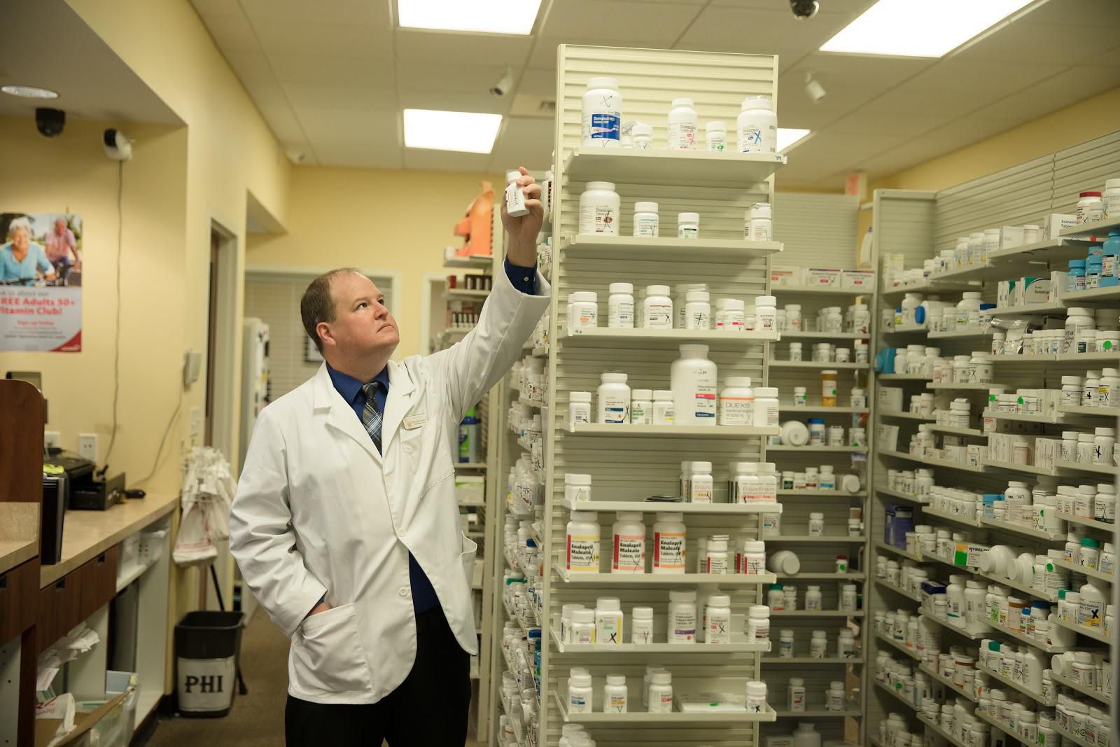 Pharmacist holding up a bottle of medicine to the light.