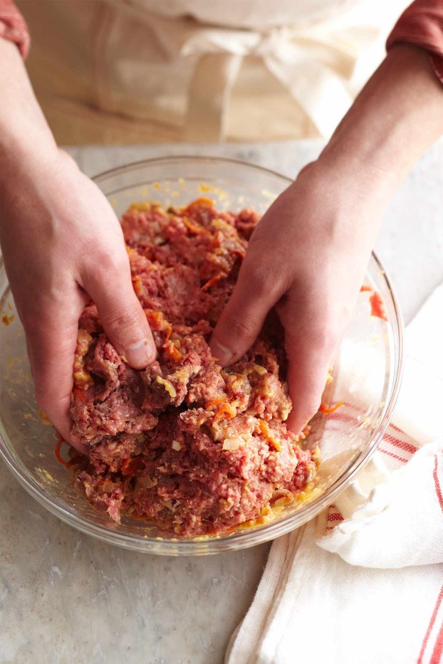 hands mixing ground beef mixture in bowl for meat loaf