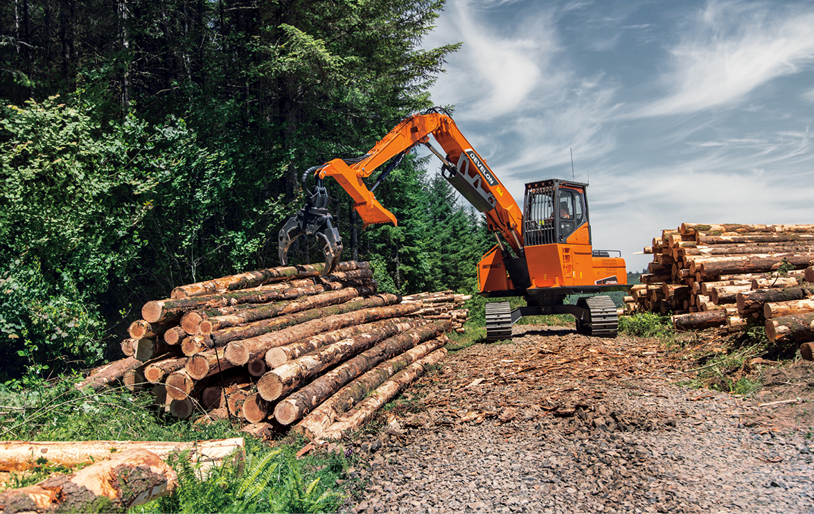 A DEVELON log loader working with a pile of timber on a job site.