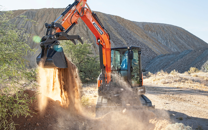 A DEVELON DX55R-7 mini excavator working on a job site.