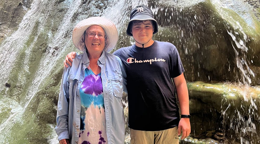 Patti with Grandson in front of waterfall 