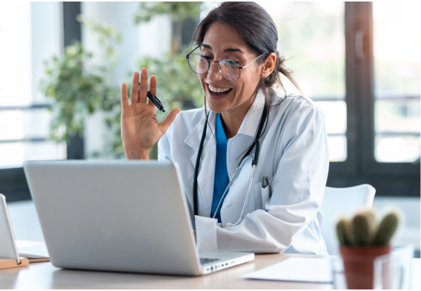 arts zwaait tijdens Zoom-gesprek op laptop